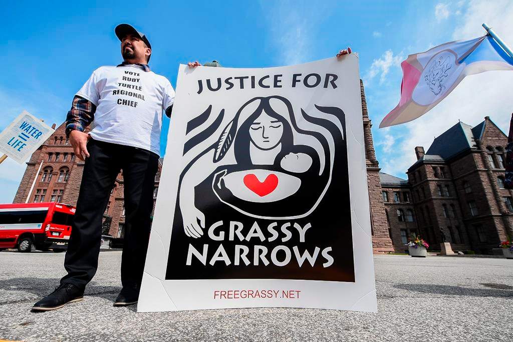 A demonstrator holds a sign following a press conference announcing intention to litigate against the Government over contamination of Grassy Narrows, in Toronto on June 4, 2024. THE CANADIAN PRESS/Christopher Katsarov.