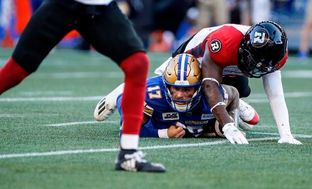 Winnipeg Blue Bombers quarterback Chris Streveler (17) gets tackled by Ottawa Redblacks' Adarius Pickett (6) during first half CFL action in Winnipeg Friday, July 5, 2024.  Ottawa (5-2) has won three straight contests and remains unbeaten at home. THE CANADIAN PRESS/John Woods.