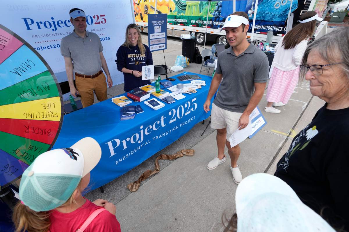 James Bacon, center, talks to fairgoers at the Project 2025 tent at the Iowa State Fair, Aug. 14, 2023, in Des Moines, Iowa. Organizers signed up hundreds of people, to build out a database of potential federal employees, inviting them to be trained in government operations.