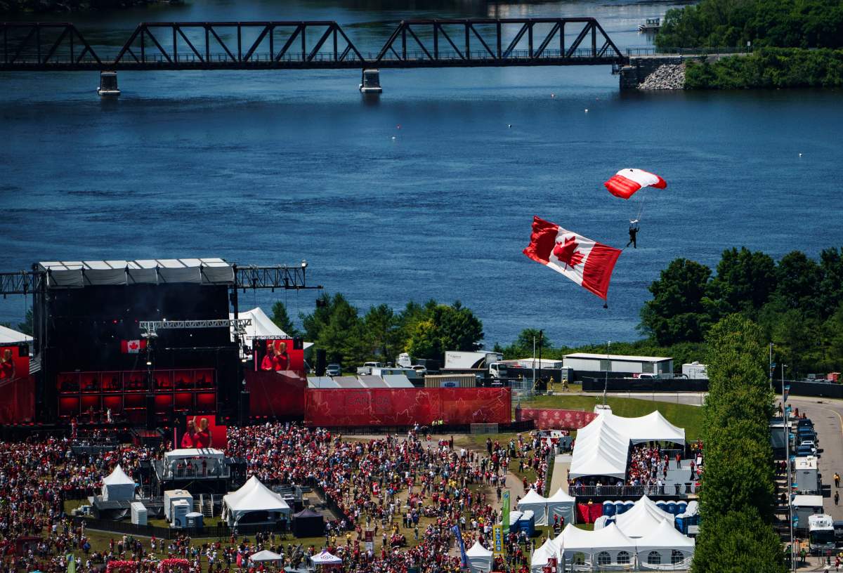 A member of the Skyhawks Parachute Team passes over people attending the Canada Day noon hour show at LeBreton Flats, during a flypast celebrating the RCAF centennial, in Ottawa, on Monday, July 1, 2024. THE CANADIAN PRESS/Justin Tang