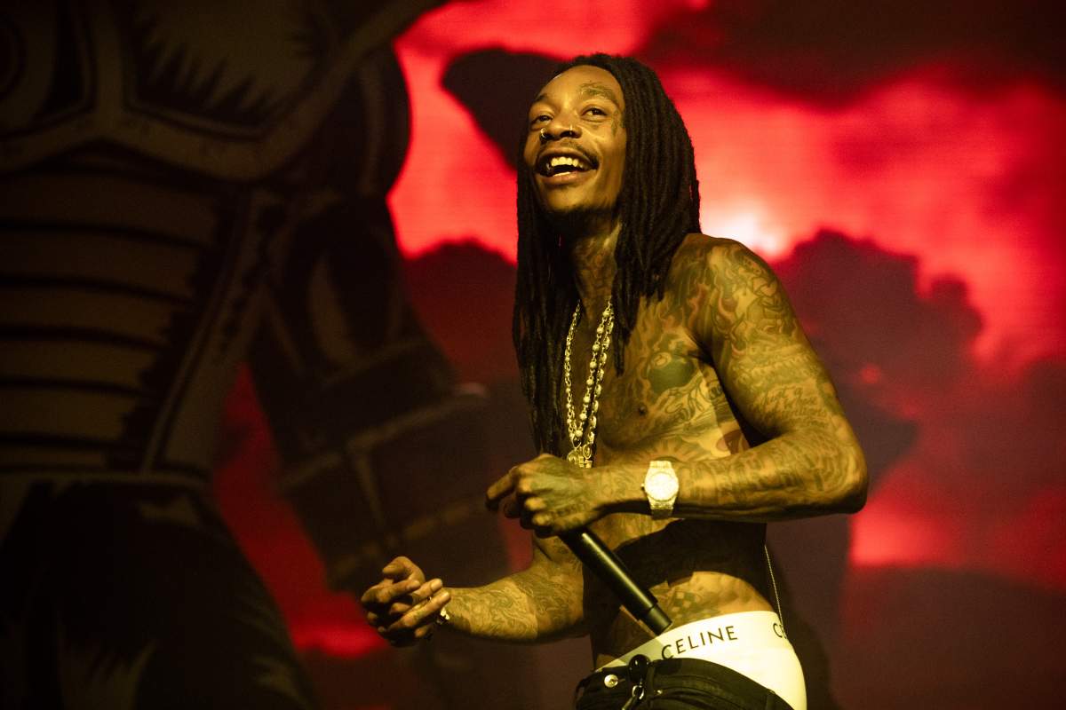 Wiz Khalifa on stgae. He is holding a microphone and has his shirt off.