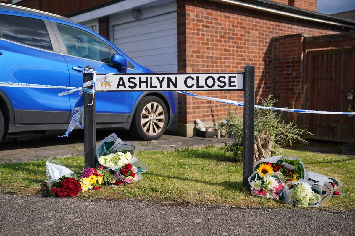A sign reading 'Ashlyn Close' surrounded by bouquets of flowers.