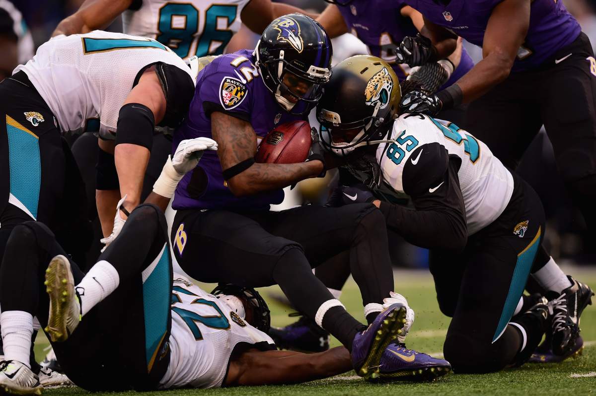 Jacoby Jones, in a Ravens uniform, holds a football as he is tackled.