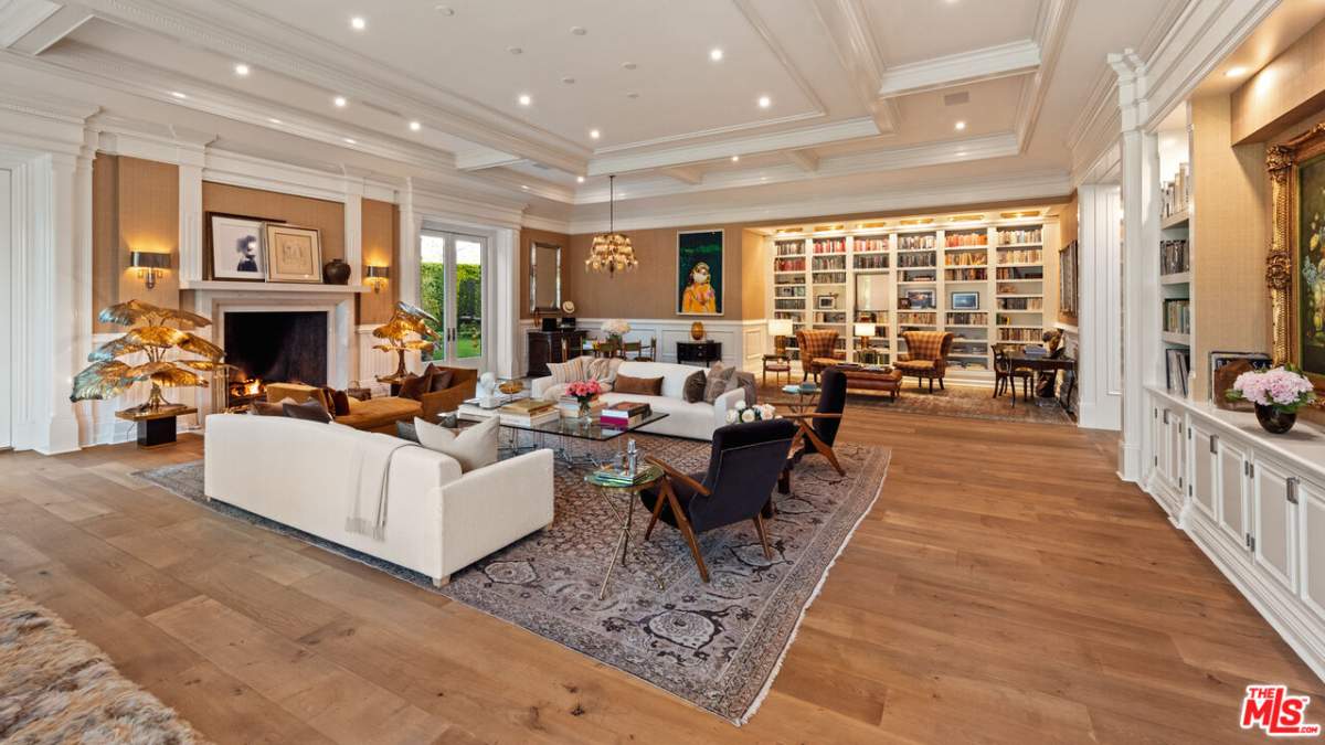 A large living room with sofas, a fireplace and a library nook.