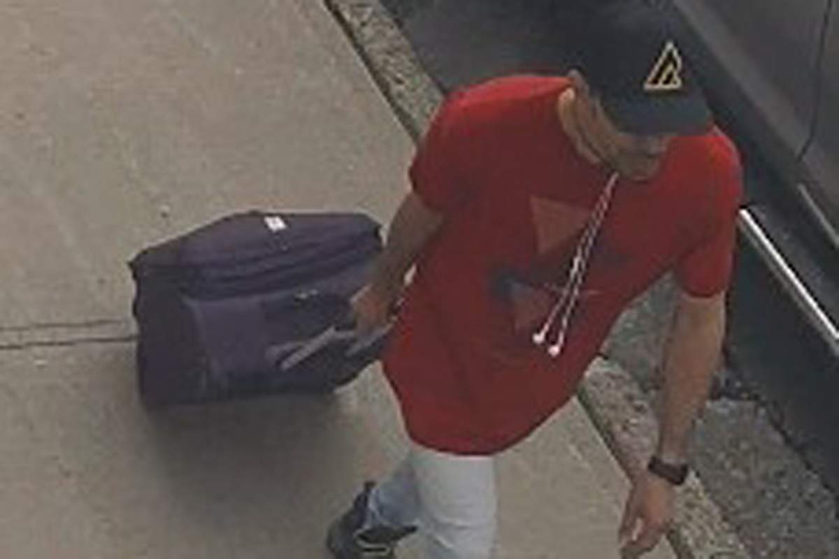 A surveillance image of a man with a suitcase.