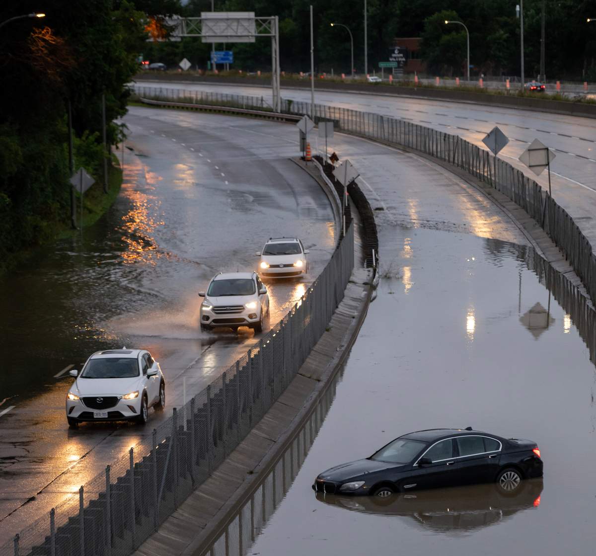 Cars drive slowly through water overflowing onto highway 40 in Sainte-Anne-de-Bellevue on the island of Montreal after heavy rains hit the area on Friday, August 9, 2024.