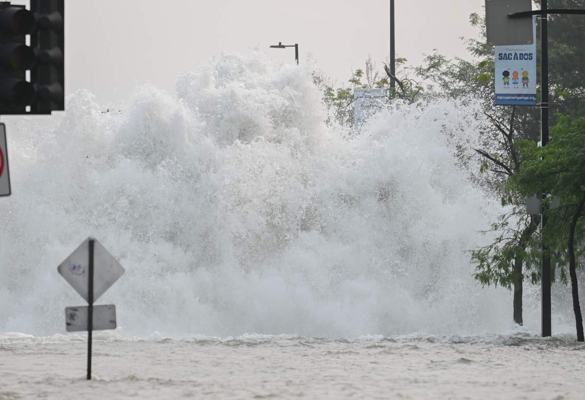 A broken watermain spews water into the air on a street in Montreal, Friday, August 16, 2024, causing flooding in several streets of the area.