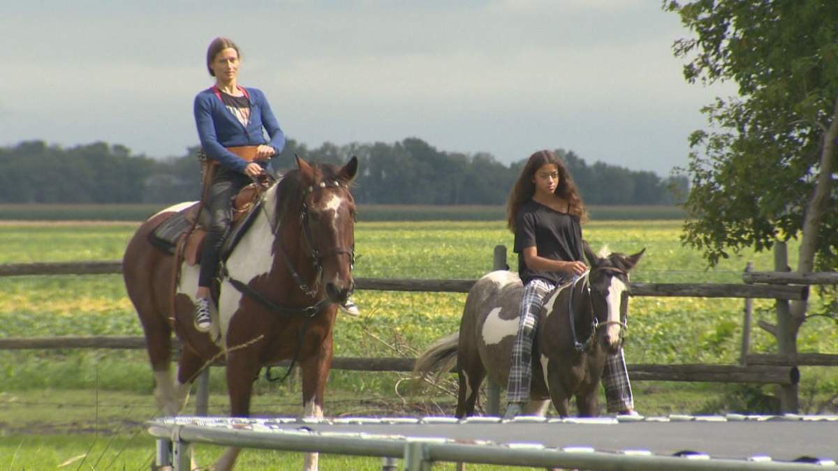 Selman riding with her daughter, Ari, on their property in Carman, Man.