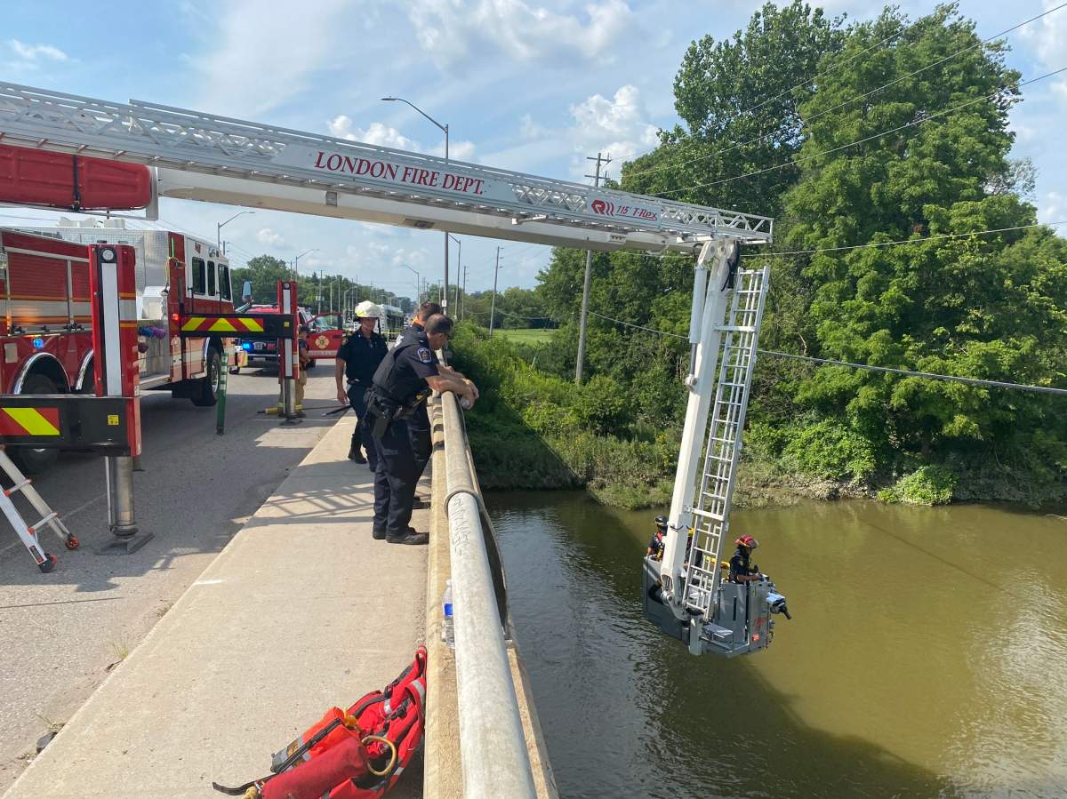Fire department equipment being deployed over a bridge into a river.