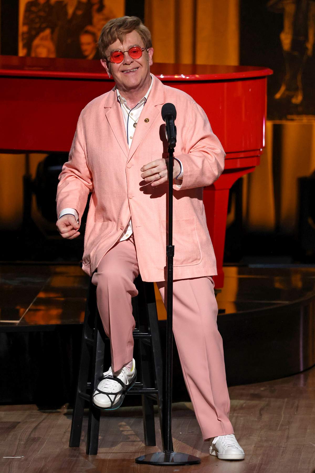Elton John on stage in a pink suit.