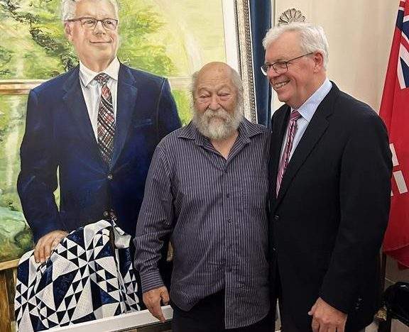 Former Manitoba premier Greg Selinger, right, poses for a photo with a supporter, next to a portrait of Selinger unveiled at the Manitoba legislature in Winnipeg on Tuesday, September 10, 2024. 