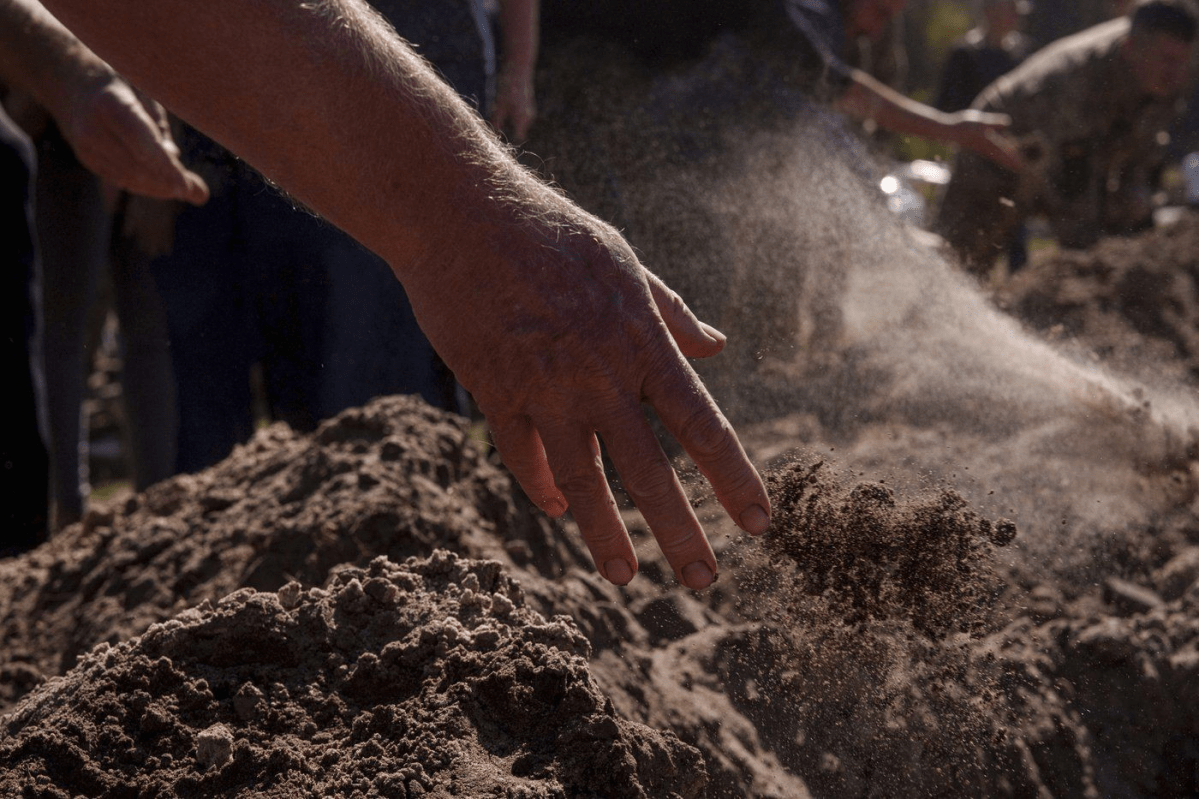 People throw three handfuls of soil into a grave during the funeral ceremony of six Ukrainian servicemen killed in a Russian rocket attack at a Ukrainian military academy, during their funeral ceremony in Poltava, Ukraine, Saturday Sept. 7, 2024. (AP Photo/Evgeniy Maloletka) Evgeniy Maloletka