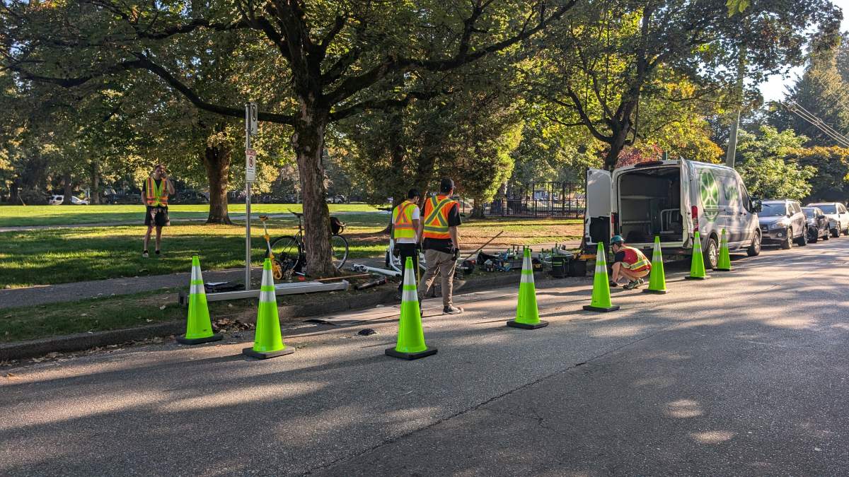 Crews install a Lime scooter parking area at Victoria Park near Commercial Drive in Vancouver.