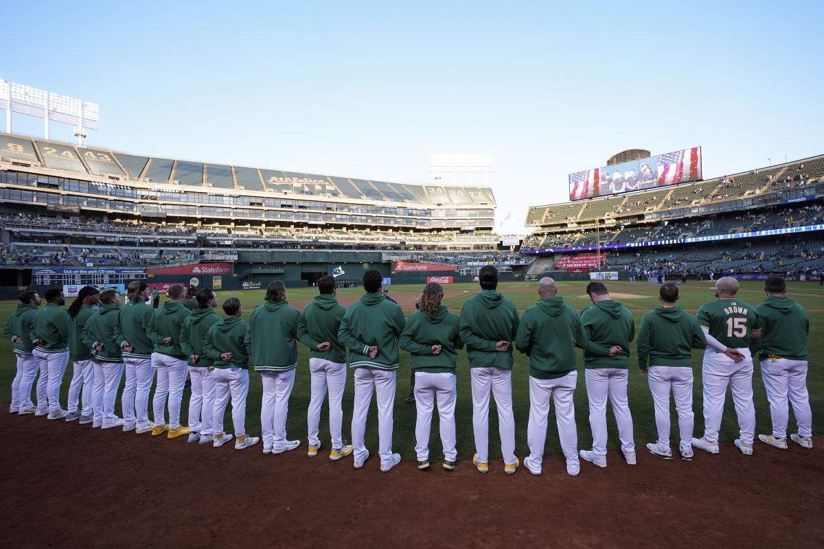 The Oakland Athletics listen to the national anthem before a baseball game against the Texas Rangers, Tuesday, Sept. 24, 2024, in Oakland, Calif.