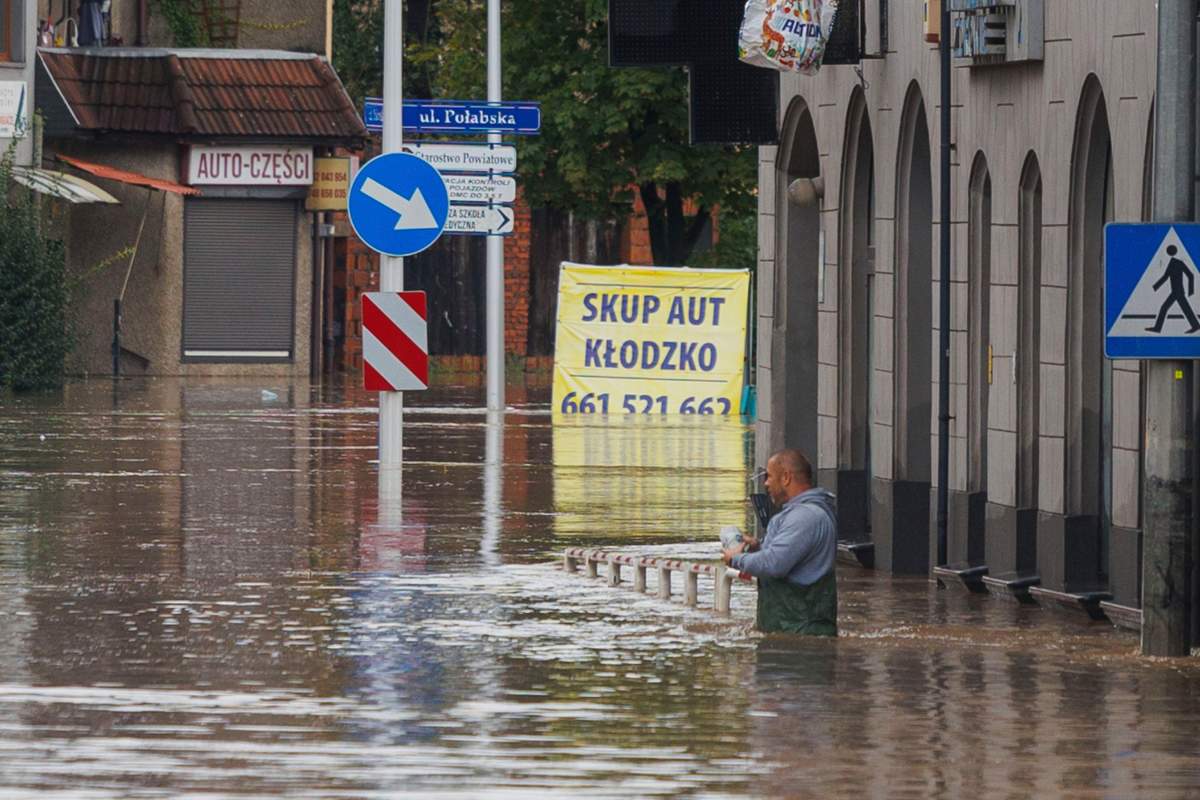 A man stands in waist-deep water that has flooded the streets and houses in the town of Kłodzko, in Poland’s southwest, on Sunday after days of unusually heavy rain. (AP Photo/Krzysztof Zatycki)