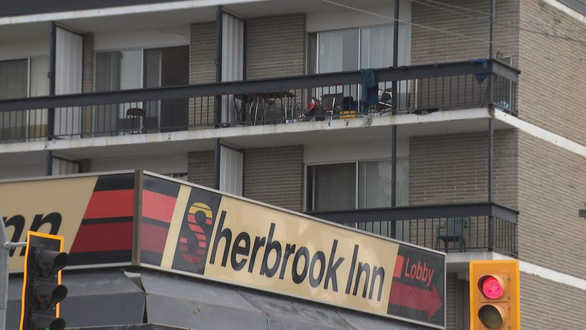 A brick building with balconies and an orange, red and white sign that reads "Sherbrook Inn"