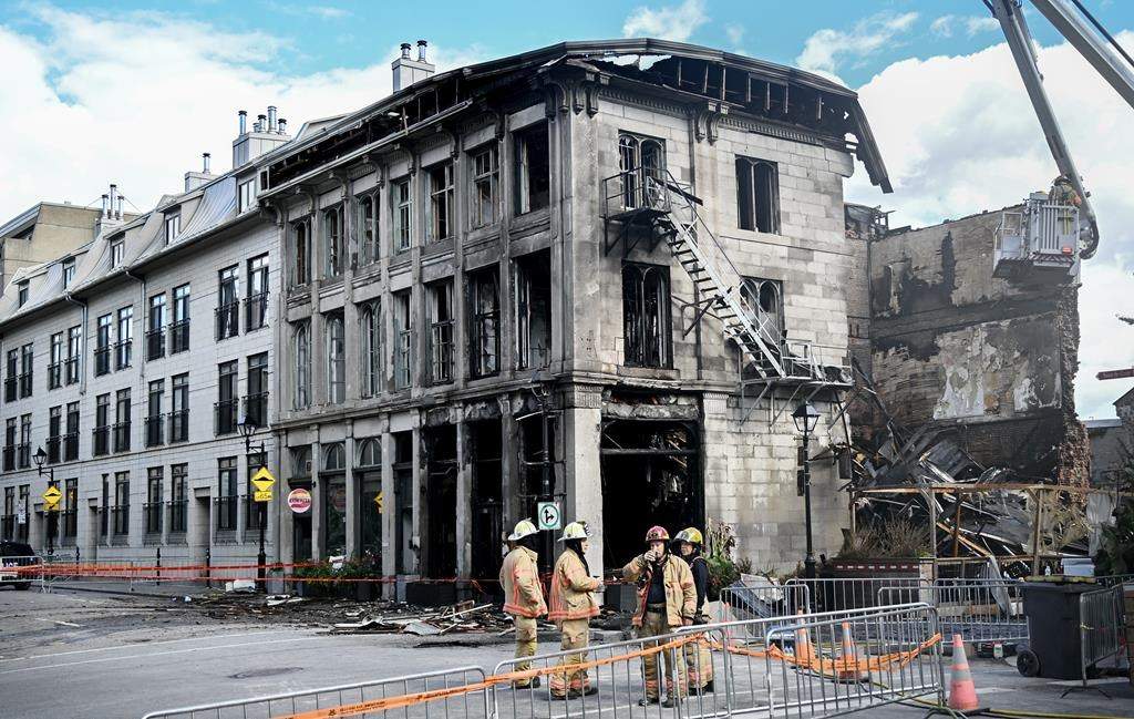 Firefighters stand next to a building in Old Montreal on Saturday, Oct., 5, 2024.