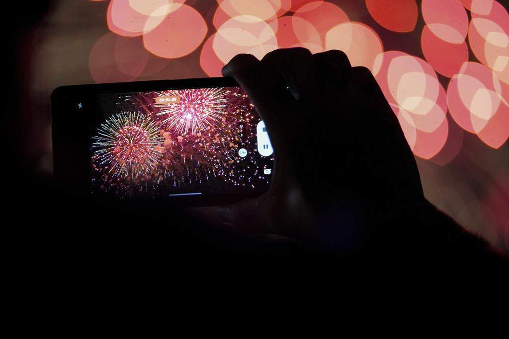 FILE - A spectator records a cell phone video as fireworks are launched over the Ohio River during the Western & Southern WEBN Fireworks show in Cincinnati on Sept. 3, 2023, in Cincinnati. (AP Photo/Aaron Doster).