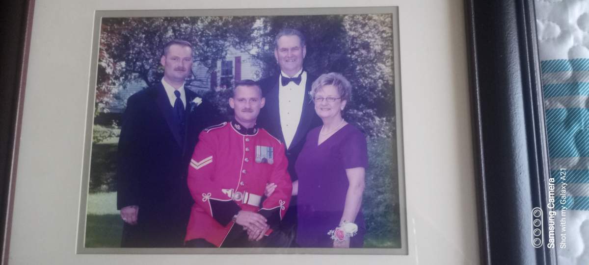 a family poses for a photo dressed for a wedding, one man is dressed in a red military dress uniform