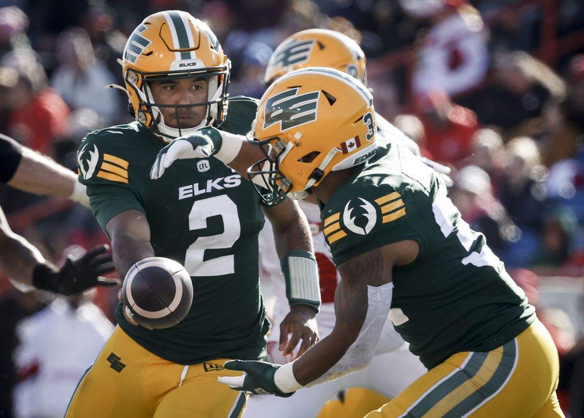 Edmonton Elks quarterback Tre Ford, left, hands the ball off to Justin Rankin during second half CFL football action in Calgary, Saturday, Oct. 12, 2024.