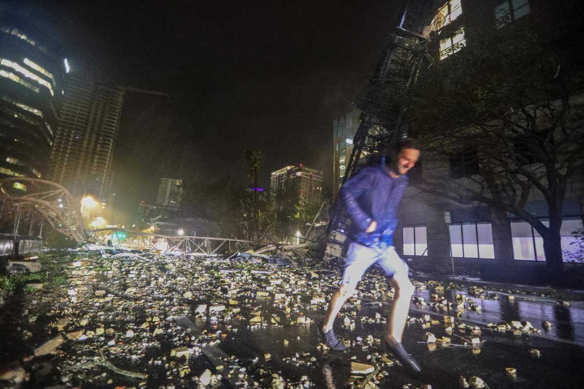 Joe Lindquist, 32, of St. Petersburg, walks over bricks near a fallen crane along 1st Avenue South near the Tampa Bay Times offices in St. Petersburg, Florida, Thursday, Oct. 10, 2024, as Hurricane Milton's strong winds tore through the area.