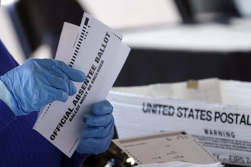 FILE - A worker at the Fulton County Board of Registration and Elections works to process absentee ballots at the State Farm Arena, Nov. 2, 2020, in Atlanta.