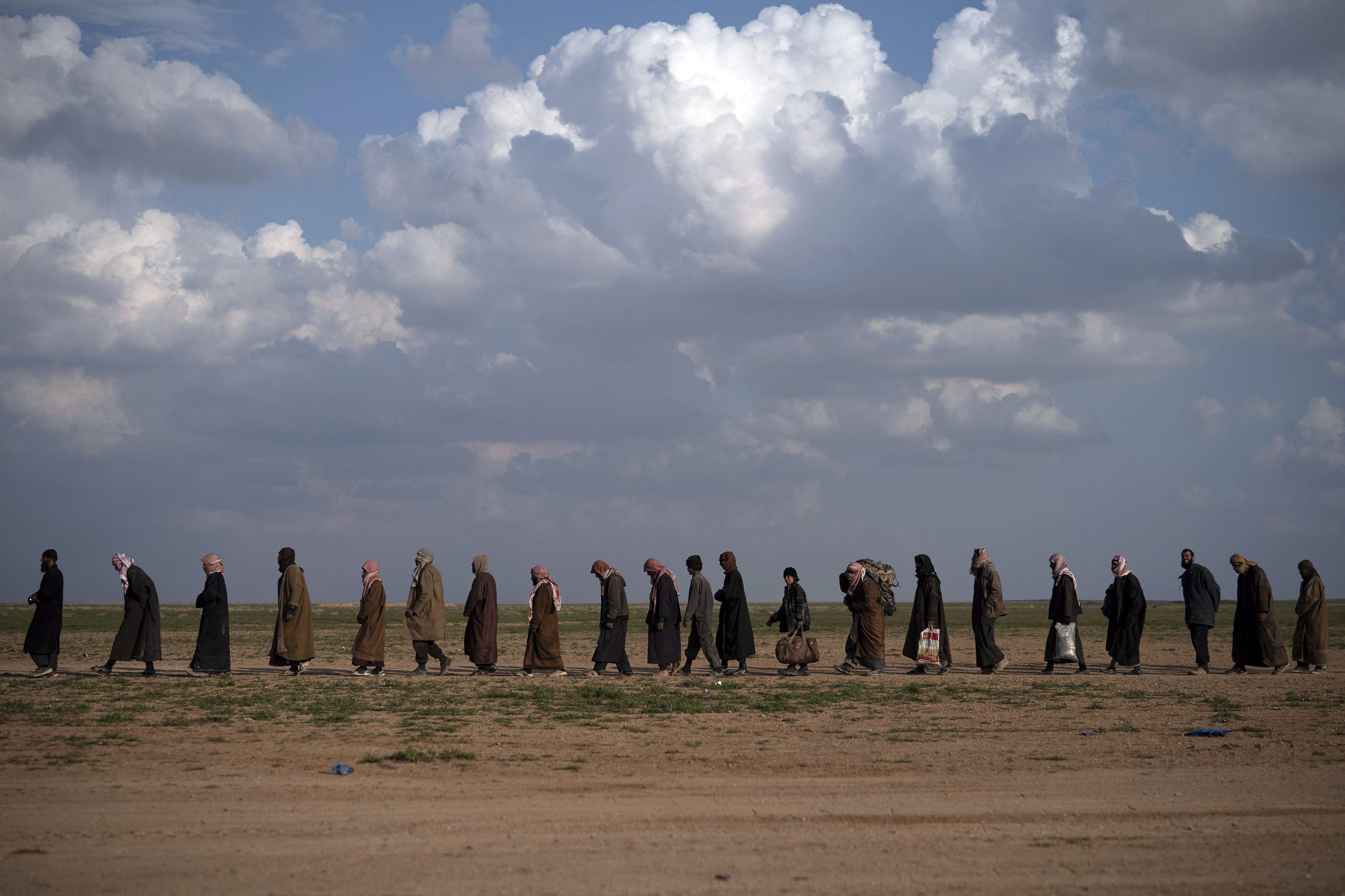Men walk to be screened after leaving the last ISIS-held territory, near Baghouz, eastern Syria, Feb. 22, 2019. (AP Photo/Felipe Dana)