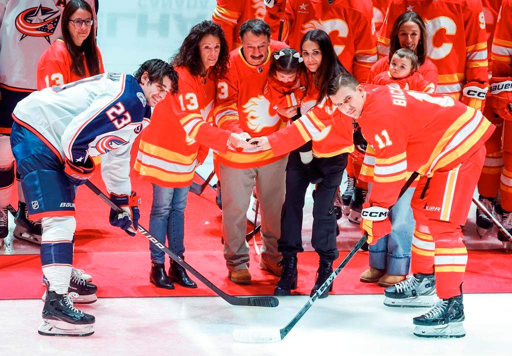 Columbus Blue Jackets' Sean Monahan, left, and Calgary Flames' Mikael Backlund join the family of Johnny Gaudreau at centre ice before first period NHL hockey action in Calgary on Tuesday, Dec. 3, 2024.