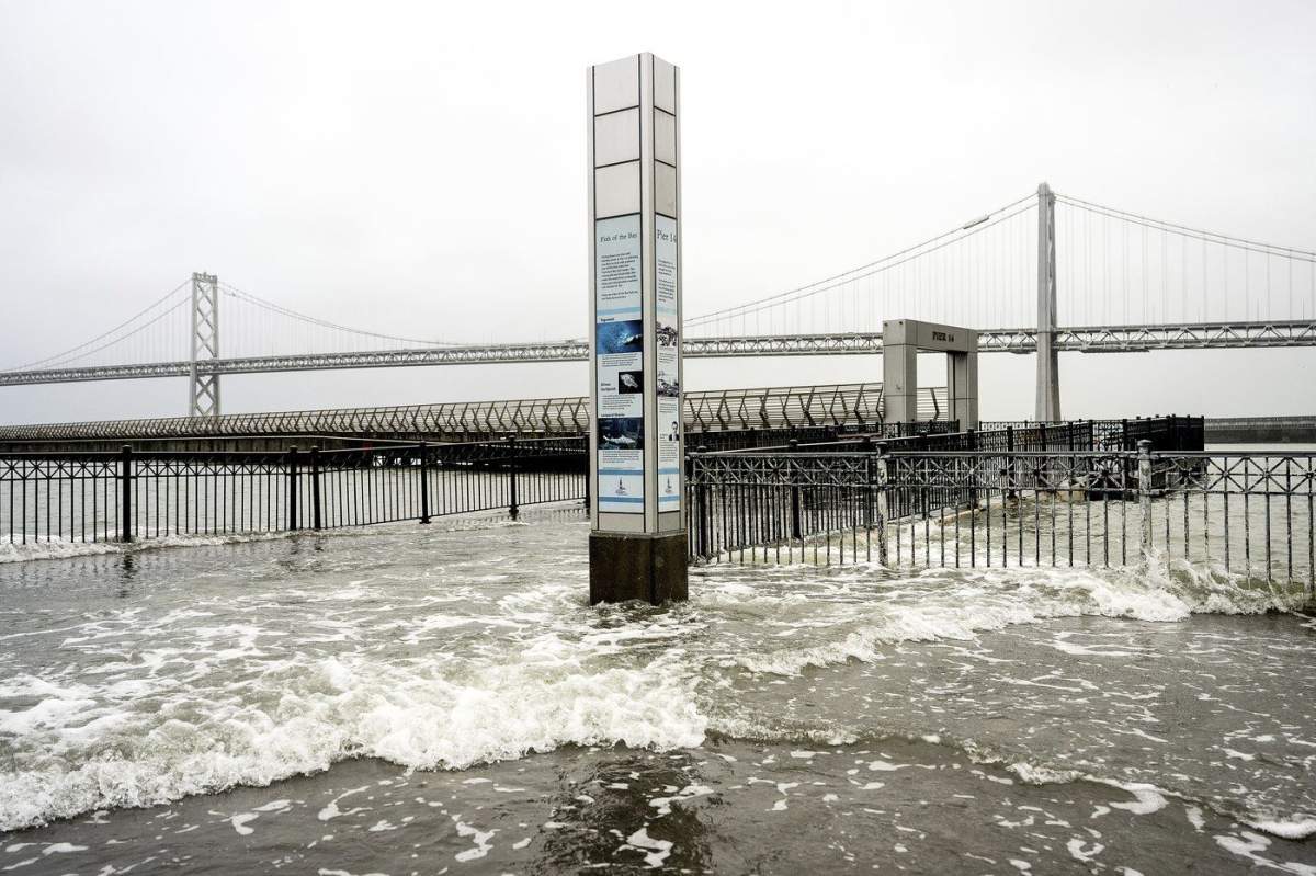 Water from the San Francisco Bay spills onto the Embarcadero in San Francisco on Saturday, Dec. 14, 2024, as a result of high tides and storm-driven waves. (AP Photo/Noah Berger)
