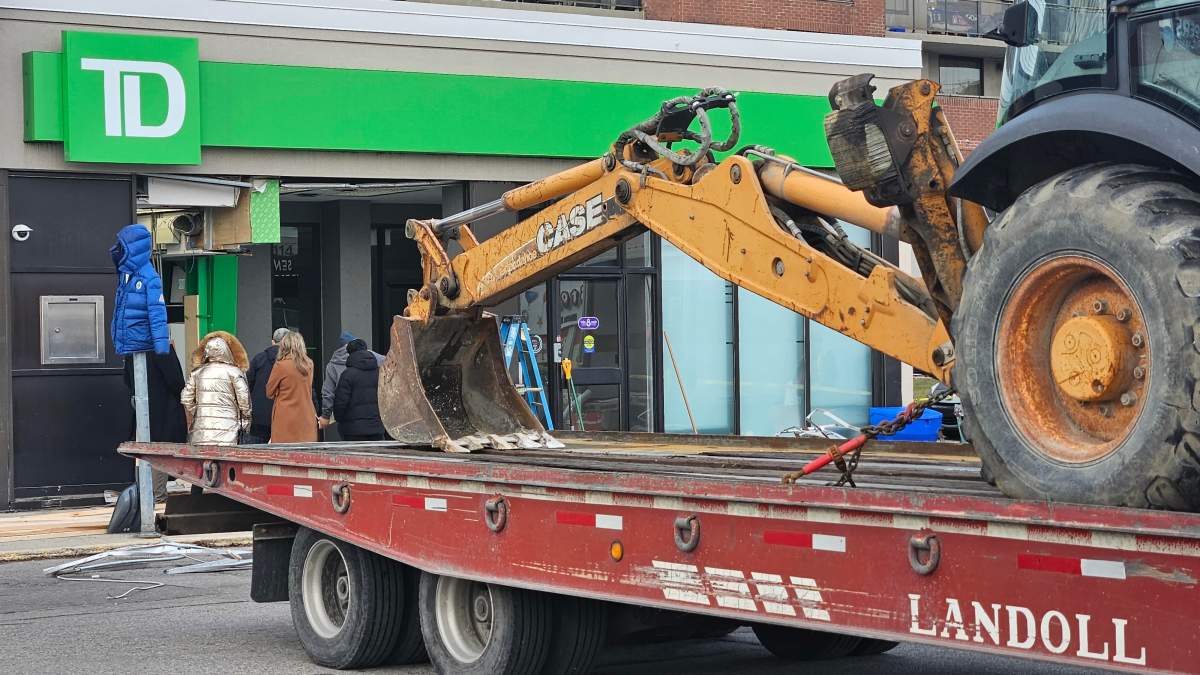 A backhoe being towed from the scene of a damaged bank, stolen ATM.