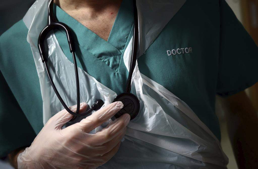 A junior doctor holds his stethoscope during a patient visit on Ward C22 at the Royal Blackburn Teaching Hospital, in Blackburn, England, Thursday, May 14, 2020.