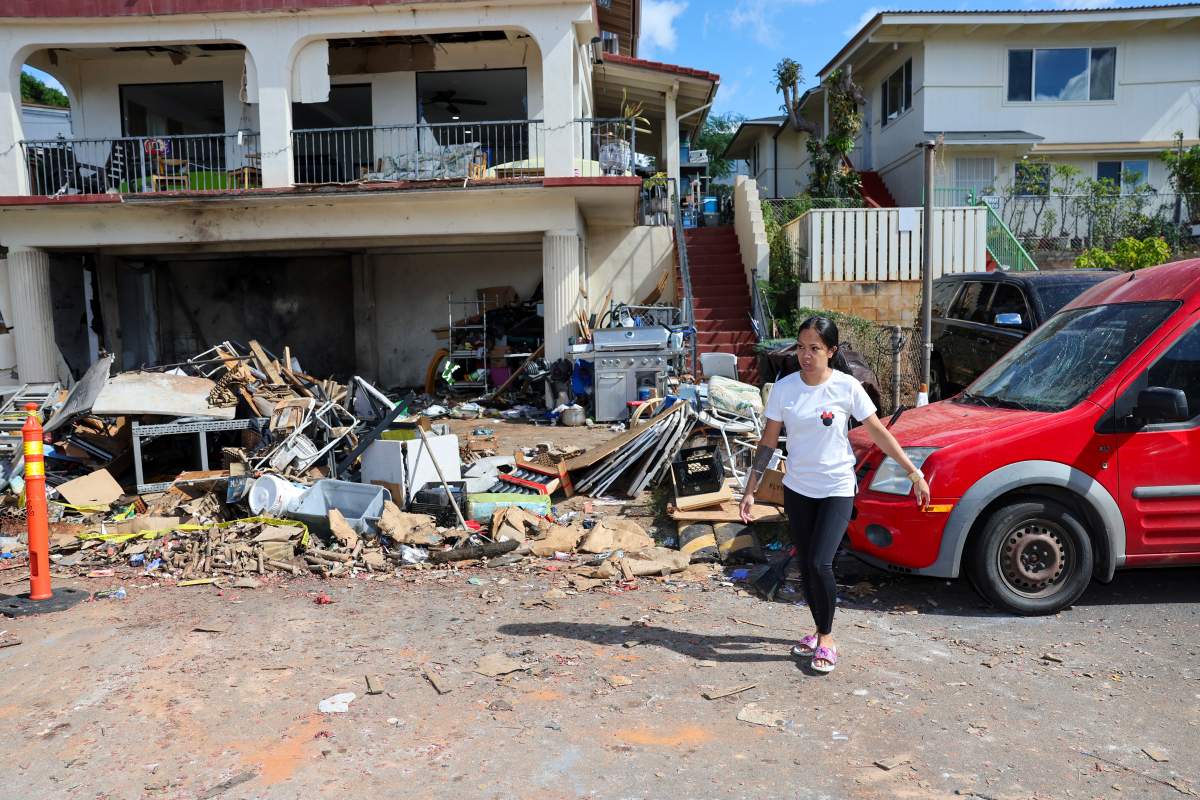 A woman walks in front of the home where a New Year’s Eve fireworks explosion killed and injured people, Wednesday, Jan. 1, 2025, in Honolulu. (AP Photo/Marco Garcia)