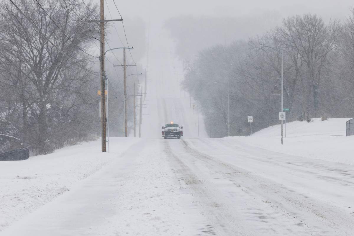 A vehicle cautiously drives down a snowy road on January 5, 2025 in Shawnee, Kansas.