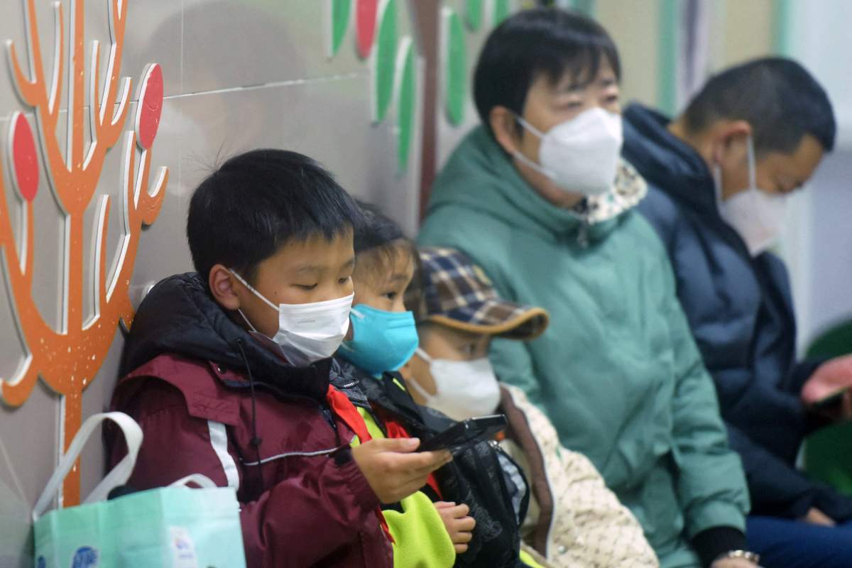Masked children, accompanied by adults, wait to be seen by medical staff at the pediatric department of a hospital in Hangzhou, eastern China's Zhejiang province, on January 6, 2025. Beijing has acknowledged a surge in cases of the flu-like human metapneumovirus (HMPV), especially among children, and attributed this to a seasonal spike. (Photo by AFP) / China OUT (Photo by STR/AFP via Getty Images)