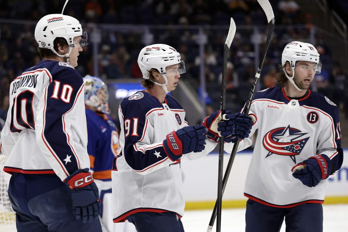 Columbus Blue Jackets centre Kent Johnson (91) is congratulated by Adam Fantilli, right, and Dmitri Voronkov (10) after scoring in the first period of an NHL hockey game against the New York Islanders, Monday, Jan. 20, 2025, in Elmont, N.Y.
