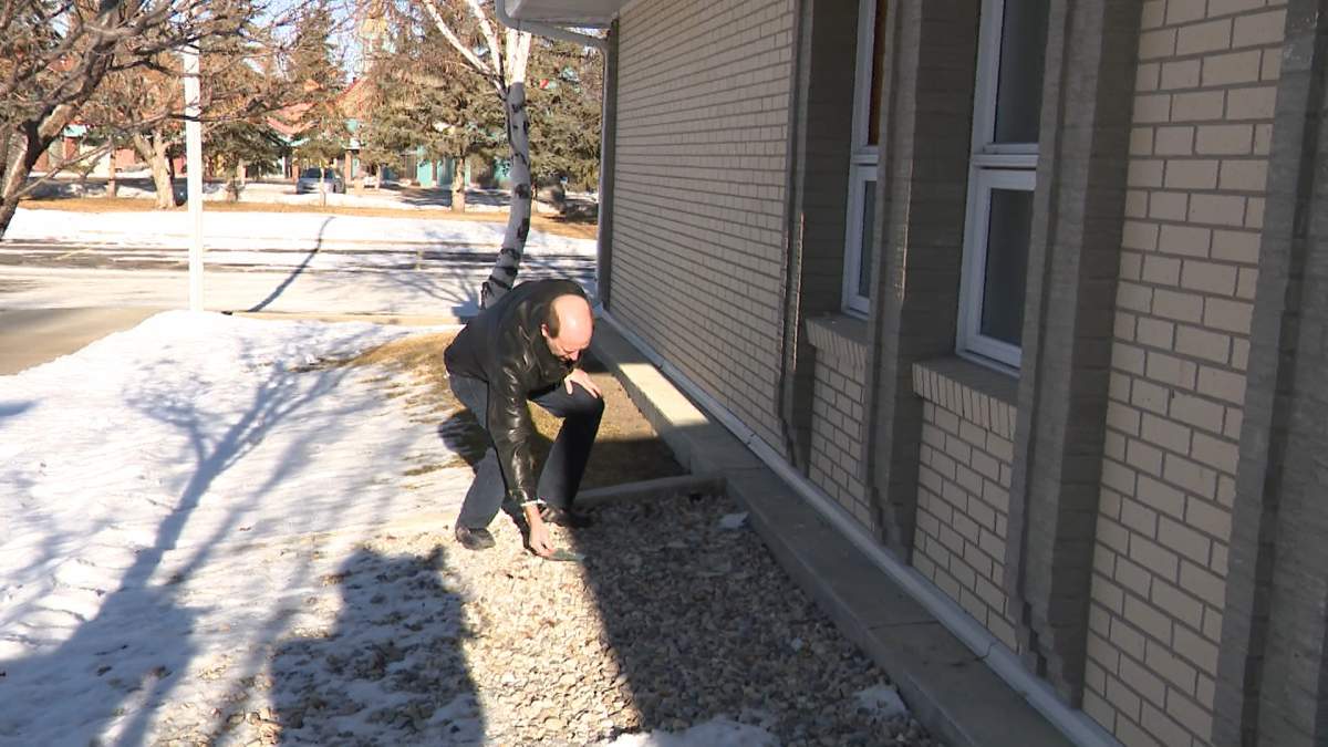 The church's Director of Communications, Greg Stringham, seen here examining some of the broken glass from the wind, says he has no idea why the church was targeted.
