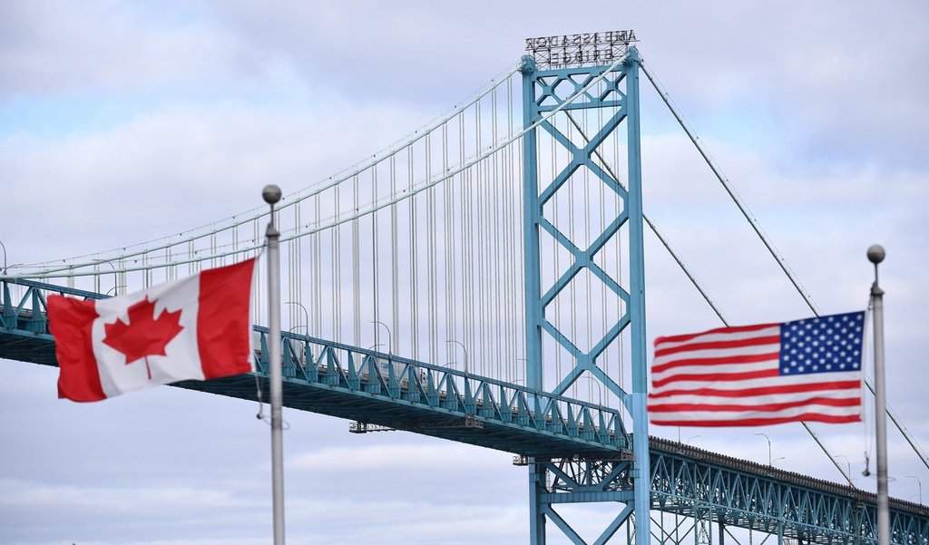 Canadian and American flags fly near the Ambassador Bridge at the Canada-USA border crossing in Windsor, Ont. on Saturday, March 21, 2020. 