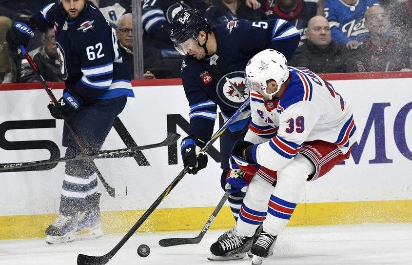 New York Rangers’ Sam Carrick (39) and Winnipeg Jets’ Luke Schenn (5) battle for the puck during the second period of their NHL hockey game in Winnipeg, Tuesday March 11, 2025.