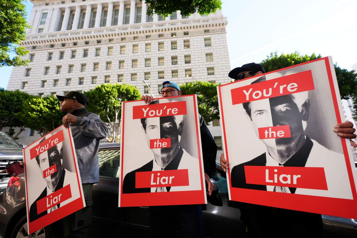 Supporters hold signs with images of District Attorney Nathan Hochman during a press conference regarding developments in the Menendez brothers case on March 20, 2025, in Los Angeles.