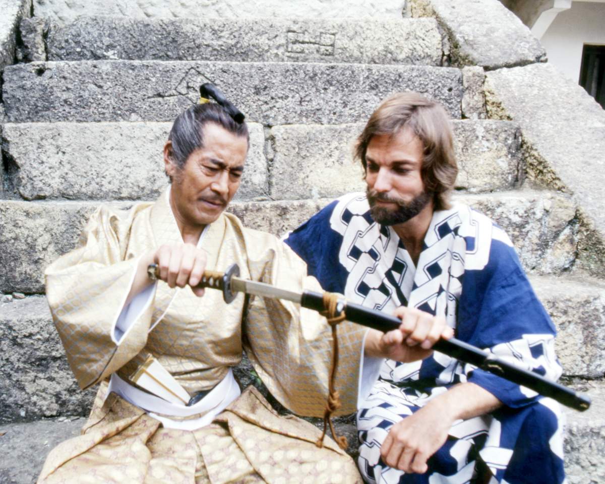 Toshiro Mifune (1920 - 1997, left), as Yoshi Toranaga, and American actor Richard Chamberlain as John Blackthorne, examine a samurai sword in the TV miniseries 'Shogun', 1980.
