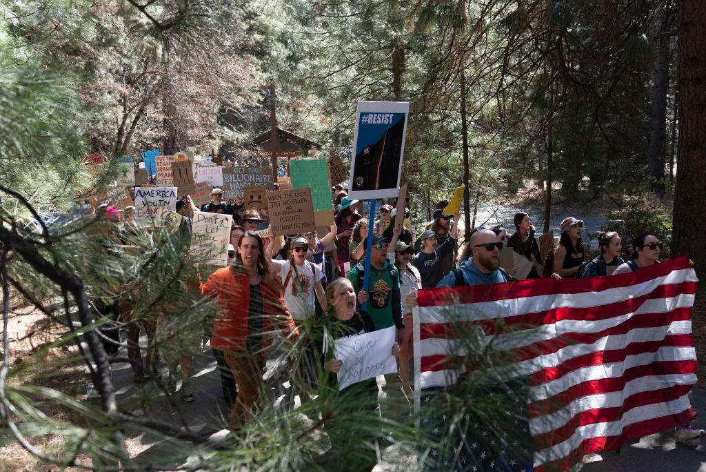 Protesters hold signs at Roosevelt Arch, the northern entrance to Yellowstone Park on March 1, 2025 in Gardiner, Montana. About 200 people showed up at the rally to protest recent firings of the National Park Service and National Forest Service Staff. Similar protests were held at many other national parks throughout the United States.