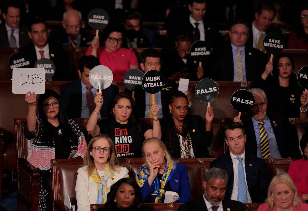 Democratic members of Congress hold up signs in protest as U.S. President Donald Trump addresses a joint session of Congress at the U.S. Capitol on March 04,(Photo by Chip Somodevilla/Getty Images)