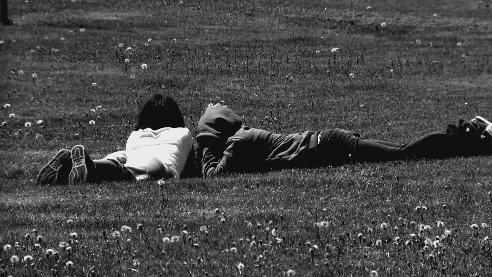 Two young kids lying on grass in a park
