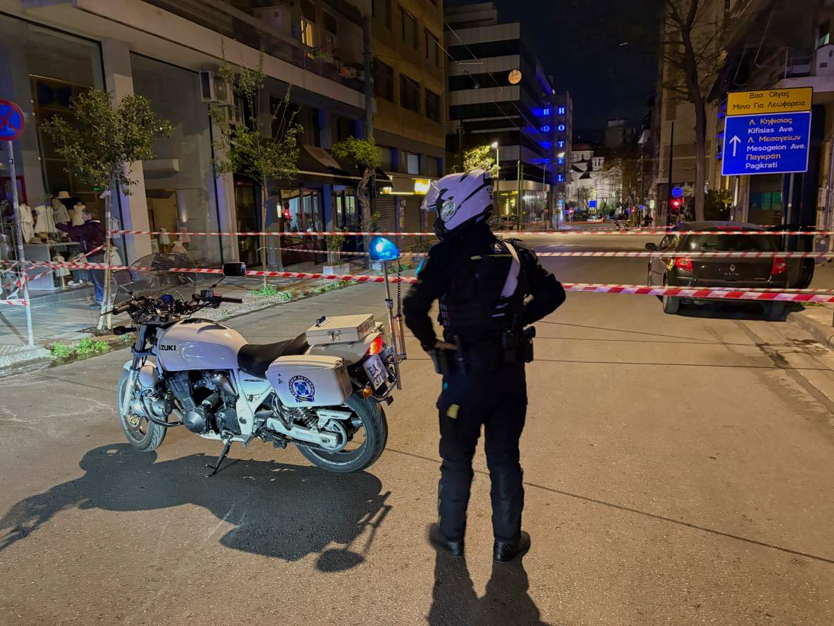 A policeman guards an area after a suspected bomb explosion outside offices of Hellenic Train the company that runs Greece's railway, the third building on the left, in Athens, Greece, Friday, April 11, 2025. (AP Photo/Derek Gatopoulos).