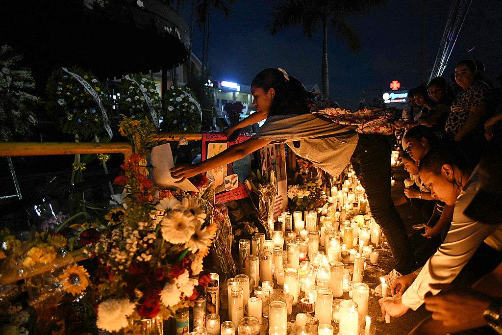 A woman places a banner as friends and relatives pay tribute to the victims in front of the Jet Set nightclub in Santo Domingo on April 12, 2025.