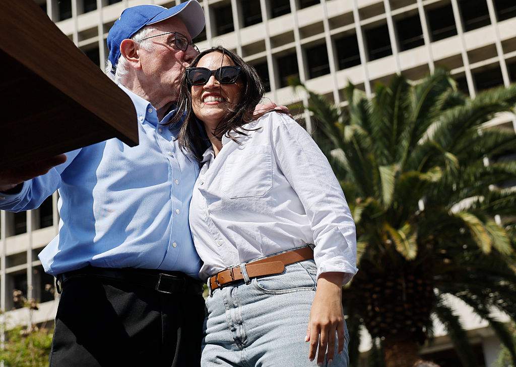 U.S. Sen. Bernie Sanders (I-VT) and Rep. Alexandria Ocasio-Cortez (D-NY) embrace during a stop on their ‘Fighting Oligarchy’ tour at Grand Park on April 12, 2025 in Los Angeles, California. An estimated 36,000 people attended the rally which also saw Neil Young and Joan Baez perform.