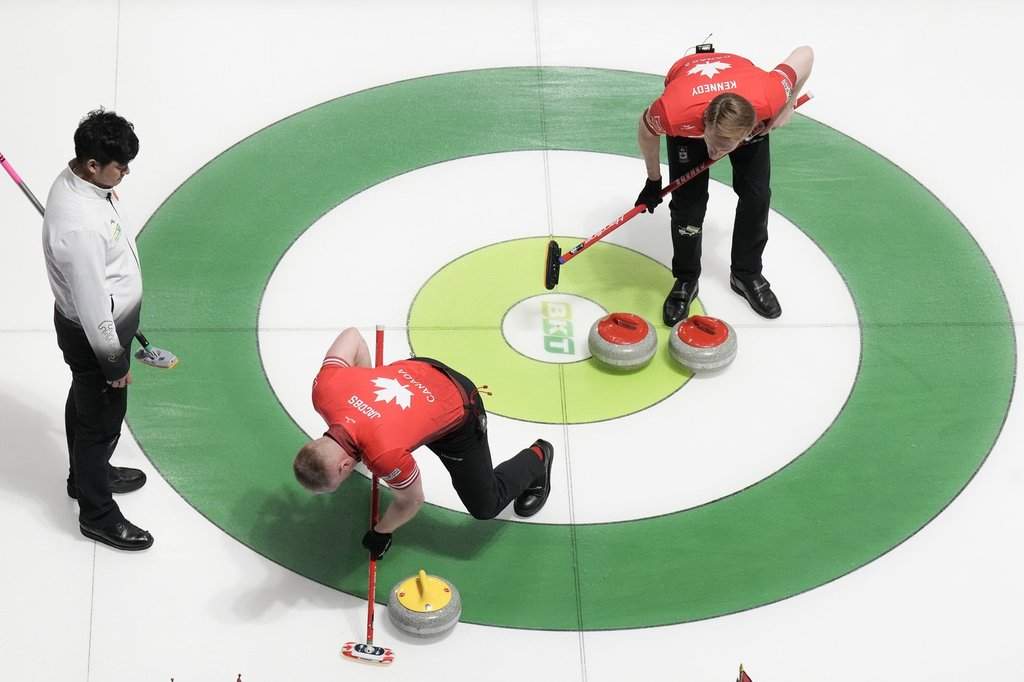 Canada skip Brad Jacobs sweeps a Chinese stone out of the house as teammate Marc Kennedy and China skip Xiaoming Xu, left, look on during BKT World Men's Curling Championship action in Moose Jaw, Sask., on Thursday, April 3, 2025.