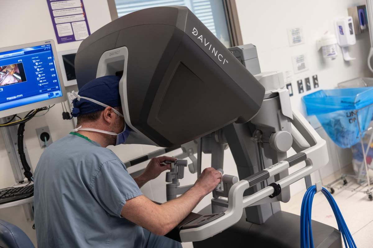 A surgeon controls the robotic system from the console, guiding the robot through the heart surgery.