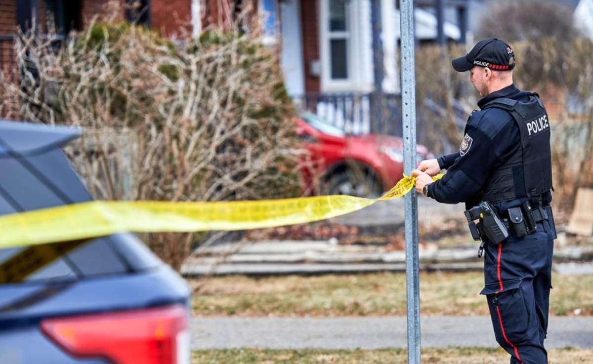 An Ottawa police officer tapes off an area in the 300 block of Craig Henry Drive while investigators search for witnesses and evidence in a Sunday morning homicide.
