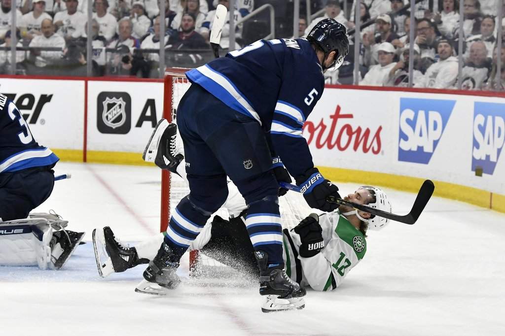 The Dallas Stars' Sam Steel (18) is checked to the ice by the Winnipeg Jets' Luke Schenn (5) during first-period NHL playoff hockey action in Winnipeg, Thursday, May 15, 2025.